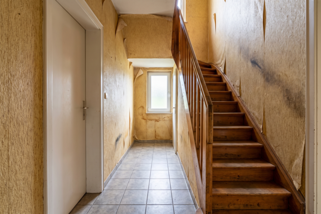 Flur mit Treppe im Saarland vor der Renovierung — vergilbte Raufasertapete, Tapezierarbeiten durch Thomas Jung
